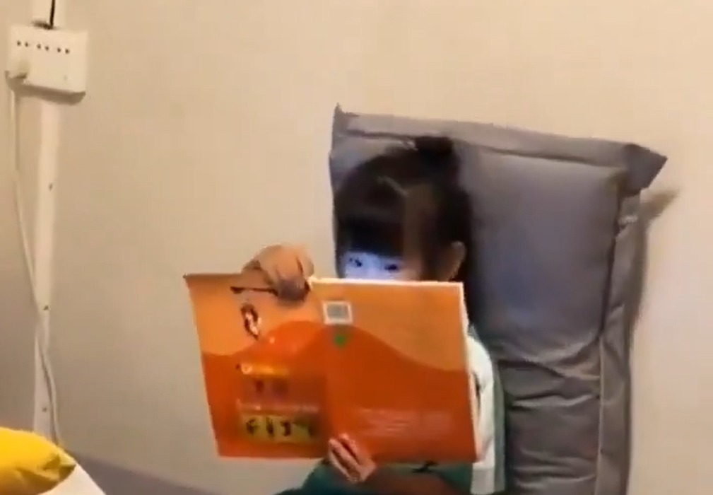 Nëna kap  mat  të bijën  libri mbrapsht dhe drita e celularit e tradhtojnë
