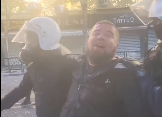 Protestuesi qesh ndërsa shoqërohet nga policia