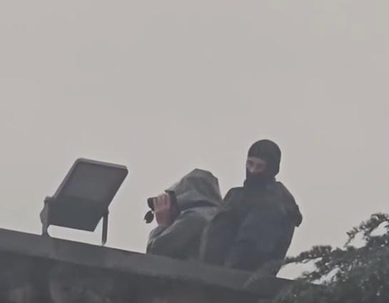 Në tarracën e Kryeministrisë, persona të maskuar vëzhgojnë protestuesit me dylbi